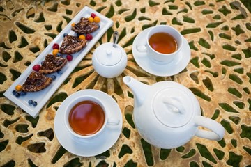 Cup of tea with dessert and teapot on table