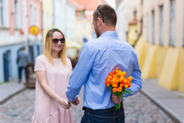Fototapeta premium love and relationship concept - young man giving flowers to his girlfriend
