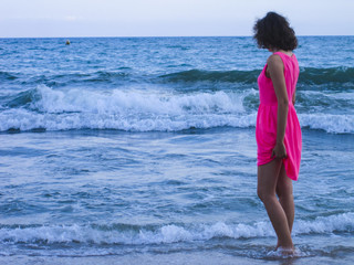 Attractive girl in pink dress looking at the sea. Bliss freedom concept. Travel.