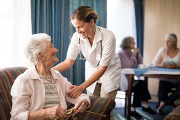 Smiling female doctor talking with senior woman - obrazy, fototapety, plakaty