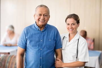 Portrait of smiling senior male patient with female doctor