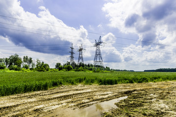 The dirt road goes along the edge of the green fields