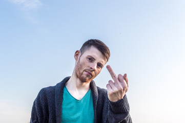 the young man shows a middle finger of a hand