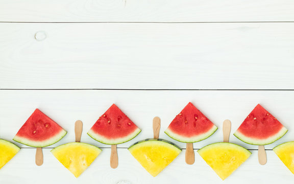 Red and yellow watermelon slices on sticks