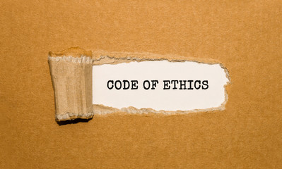 The text code of ethics appearing behind torn brown paper