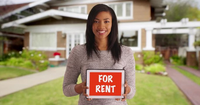 Portrait of cheerful black female advertising home for rent