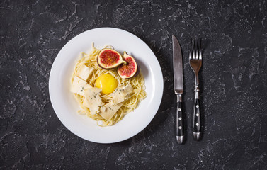 freshly cooked pasta with figs, egg yolk, cheese over a rustic stone board. Top View