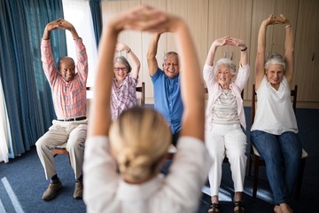 Cheerful senior men and women exercising with female doctor