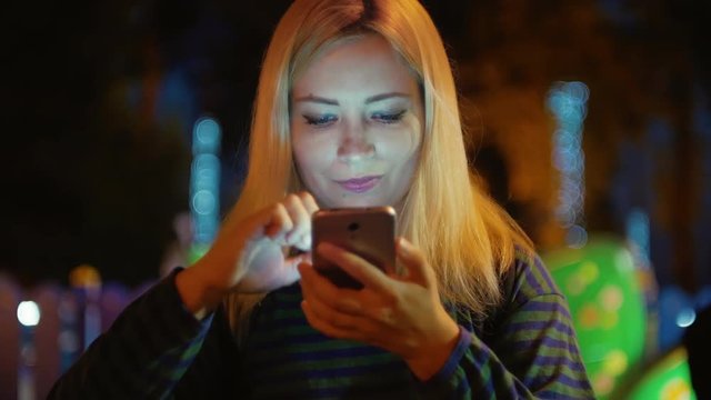 Young blond hair beautiful girl with mobile phone at night city looks photo
