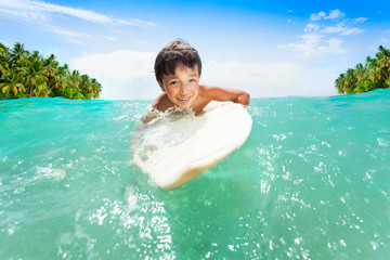 Boy swims on the surfing board in sea waves