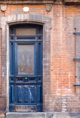 Fototapeta na wymiar Old rustic blue narrow tall wooden door in historic house in Toulouse