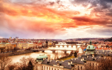 Classic spectacular scenery of Prague. Bridge vista over Vltava river beneath the epic and dramatic sunset sky in winter season. Prague is famous and very popular travel destination city in Europe.