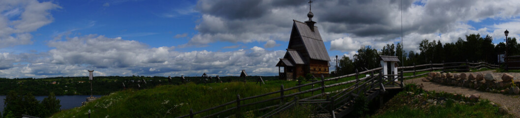 Wooden temple and rural cemetery on the hill/A wooden Orthodox church stands on a hill. Near the church there is an ancient rural cemetery with wooden crosses. Plyos, the Golden ring of Russia
