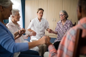 Female doctor meditating while holding hands with seniors