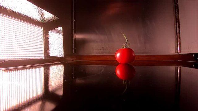Floodlight lights up the falling of a tomato in slow motion
