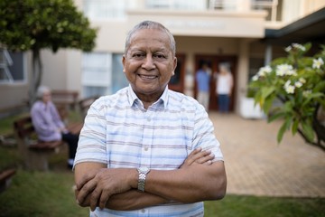 Portrait of smiling senior man standing with arms crossed
