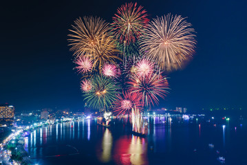 Colourful Fireworks over the sea beach with blue twilight sky background and city view