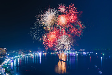 Colourful Fireworks over the sea beach with blue twilight sky background and city view