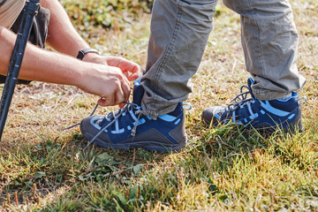 Close-up view of father tying shoelace for son during hiking in forest