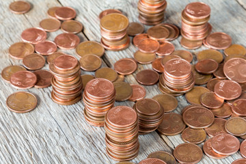Euro cents stacked on wooden background.