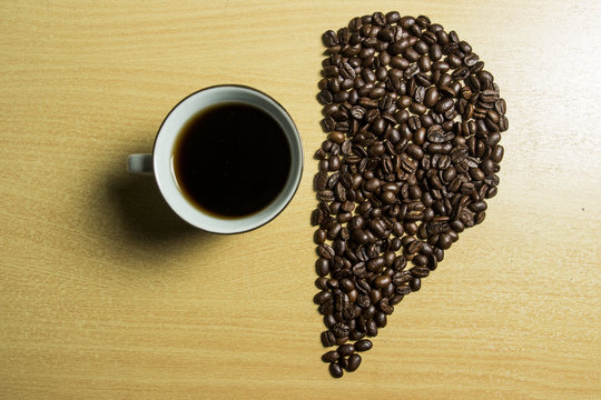 coffee concept - roasted coffee beans and coffee cup in the middle with shape half love. 