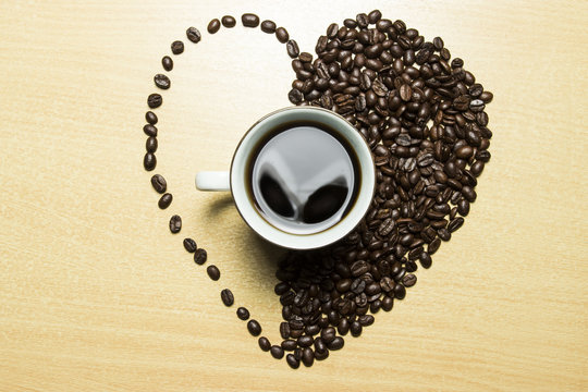 coffee concept - roasted coffee beans and coffee cup in the middle with shape love. 