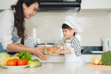 Child helping mother cooking in modern kitchen