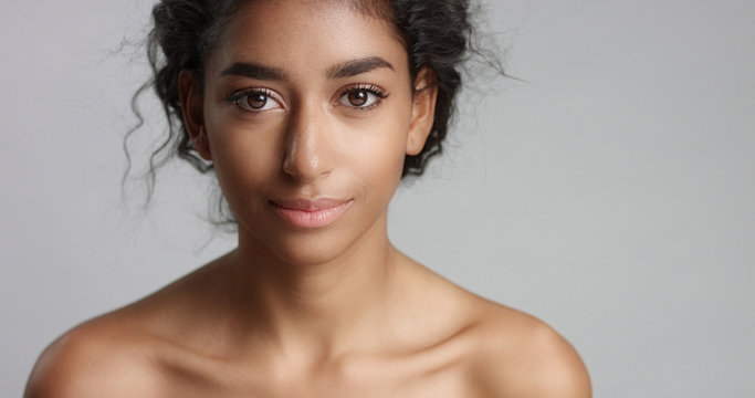 happy serene young woman with beautiful olive skin and curly hair ideal skin and brown eyes