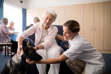 Portrait of smiling female doctor kneeling by senior woman