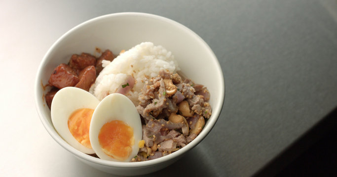 Serving Asian style soup with rice, pork, hardboiled egg and eggplant by pouring hot stock