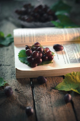 Autumn still life: Grapes with a book on a wooden background.