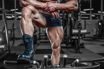Handsome model young man training legs in gym