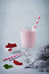 Red currant yoghurt smoothies, milkshake in a glass cup on a gray concrete background. Selective focus. Copy space.