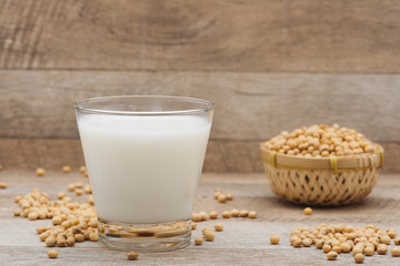 Glass with soy milk and soy bean on wooden background