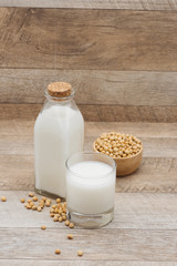 Bottle of soy milk and soybean on wooden table