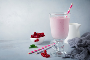 Red currant yoghurt smoothies, milkshake in a glass cup on a gray concrete background. Selective focus. Copy space.