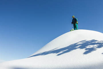 Man skier freerider standing at top of ridge, adventure winter freeride extreme sport
