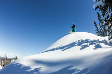 Man skier freerider standing at top of ridge, adventure winter freeride extreme sport