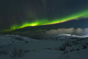 Winter, night, frozen lake and aurora borealis above the hills .