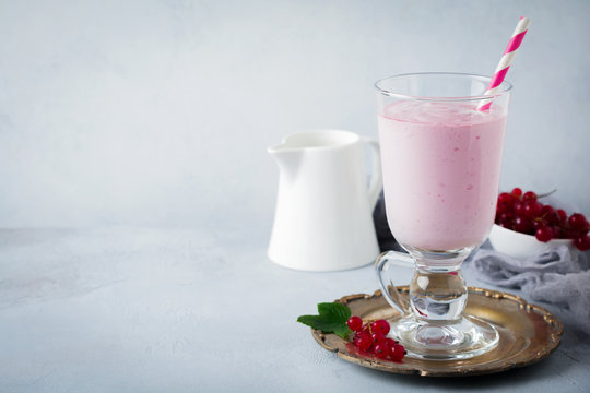 Red currant yoghurt smoothies, milkshake in a glass cup on a gray concrete background. Selective focus. Copy space.