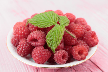 Raspberries in a bowl on a wooden table pink