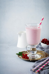 Red currant yoghurt smoothies, milkshake in a glass cup on a gray concrete background. Selective focus. Copy space.