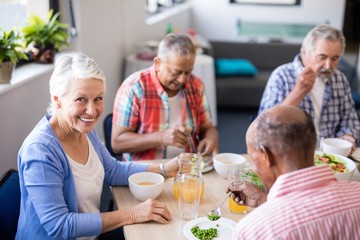 Portrait of senior woman sitting with friends while having
