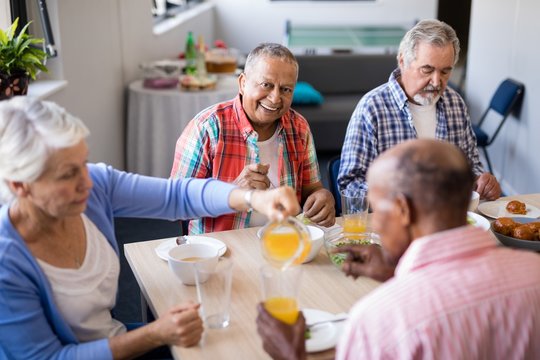 High angle view of woman serving drink to senior friends