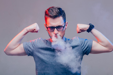 Men with beard in sunglasses vaping and releases a cloud of vapor in nose
