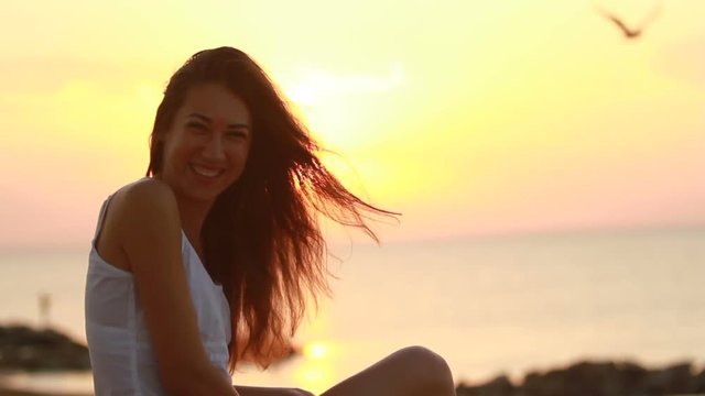 Happy young woman smiling on morning beach while imaging the playing with sun
