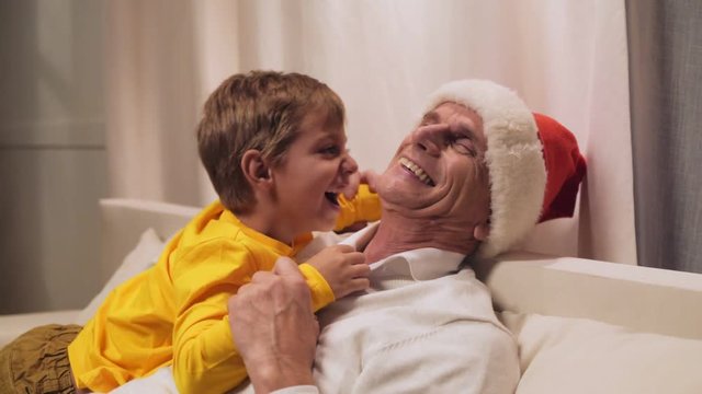 Joyful aged man resting with his grandson at home
