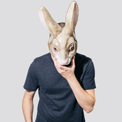 Man wearing mask of rabbit on plain background