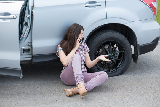 Woman With Flat Tire On Car Phoning For Assistance