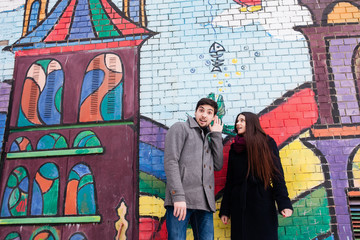couple in love on the background of a painted wall in winter in a coat